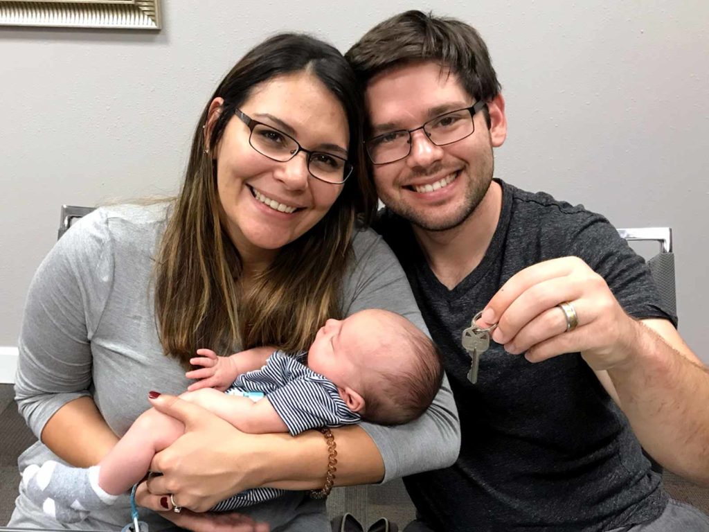 husband and wife with baby and new house keys.
