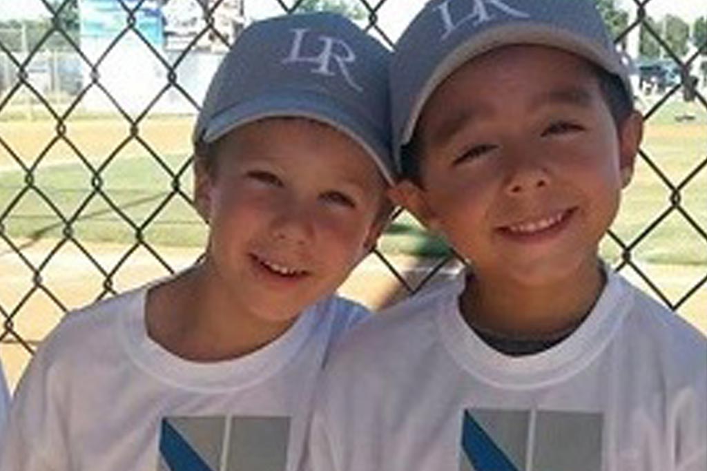 two boys in baseball uniforms smiling.