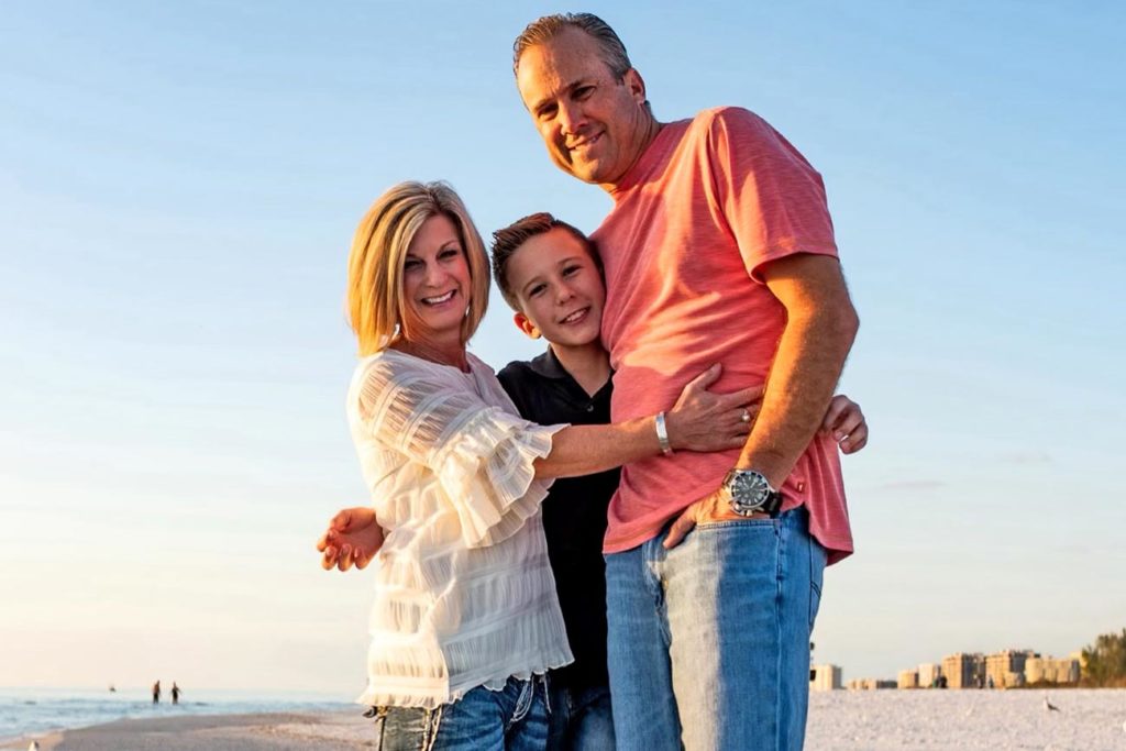 Family smiling for picture at beach.