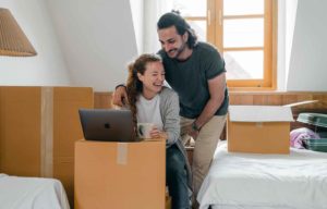 Couple laughing while reading computer atop a box