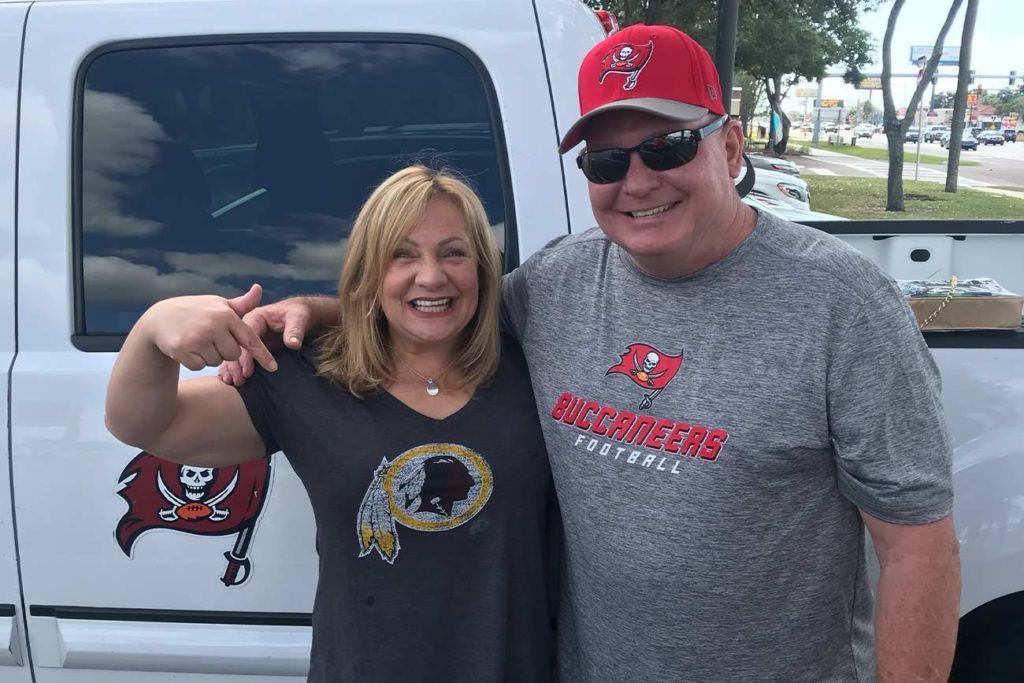 Pam standing next to her husband tailgating