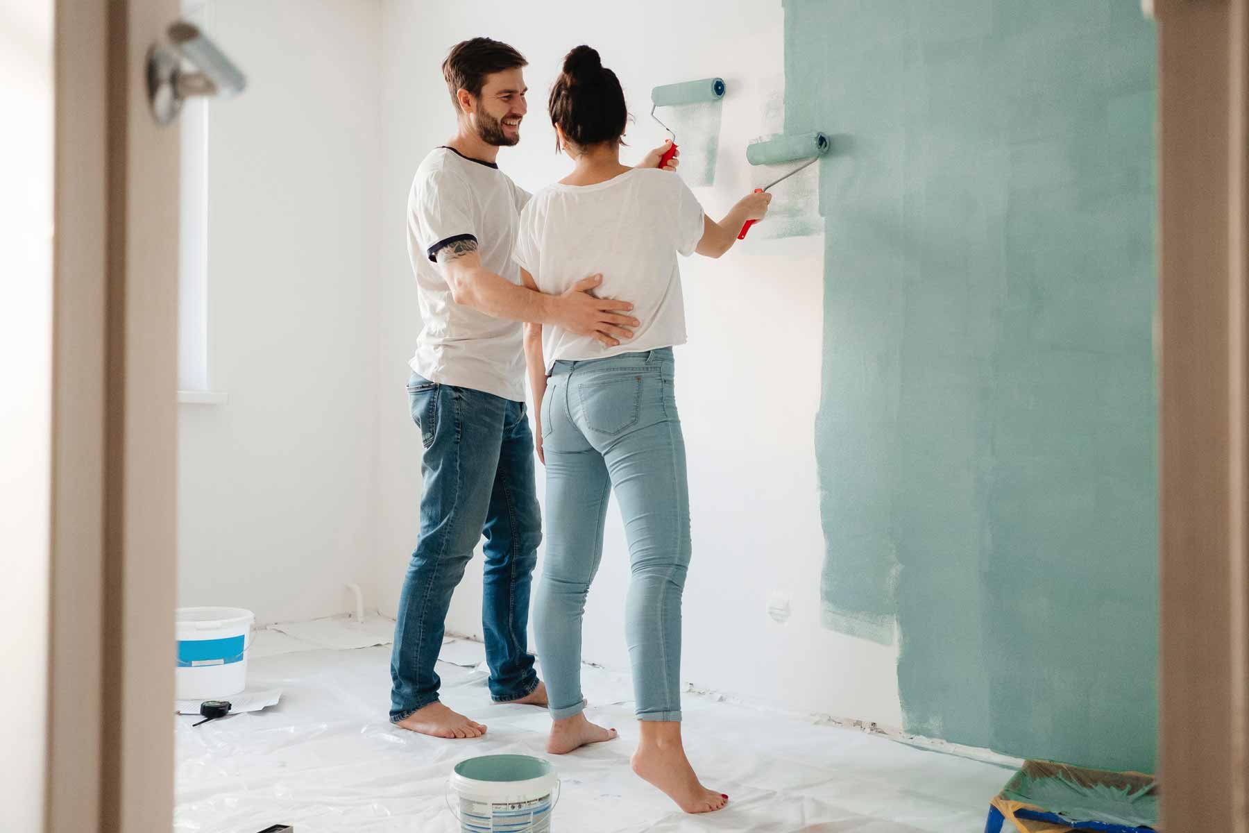 man and woman painting wall with rollers