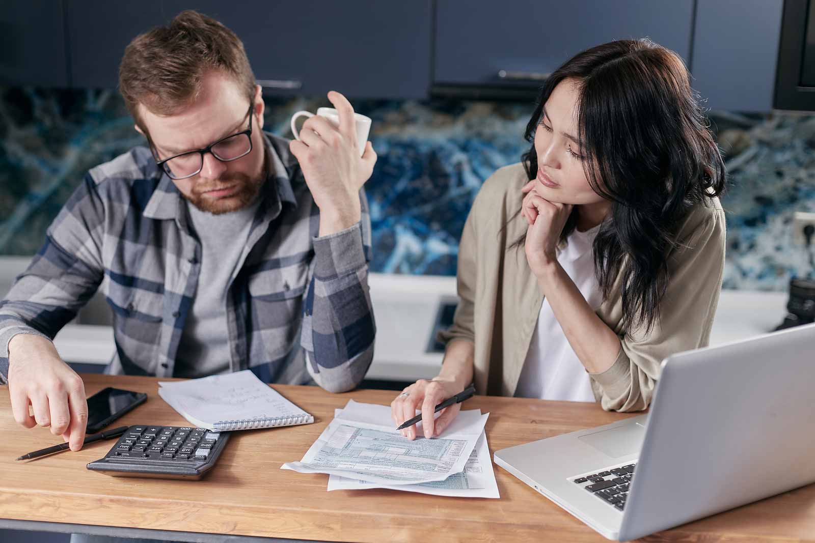 man and woman sitting at desk paying bills with computer