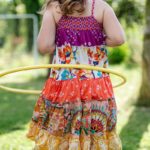 Girl in colorful dress hula hooping outdoors