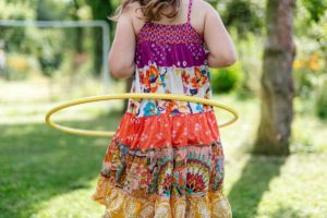 Girl in colorful dress hula hooping outdoors