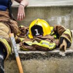 Firefighter sitting on steps with helmet next to them.