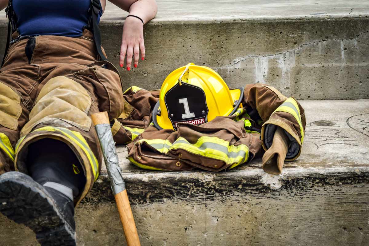 Firefighter sitting on steps with helmet next to them.