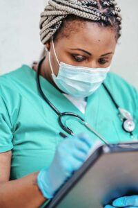 Nurse with mask writing on a clipboard.
