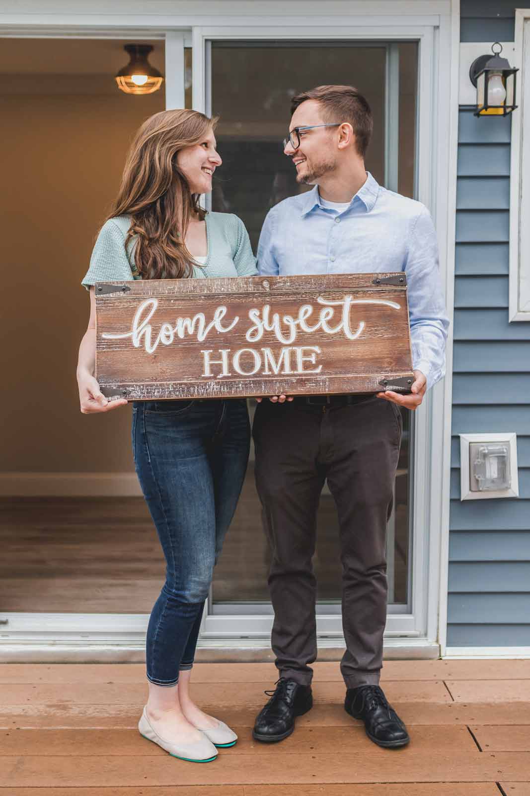 woman and man holding sign that says home sweet home